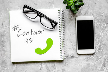 customer support service desktop with contact us signs on gray background top view