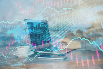 Double exposure of businessman's hands with laptop and stock market graph background. Concept of research and trading.
