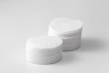 Two piles of cotton pads with a shadow on the gray