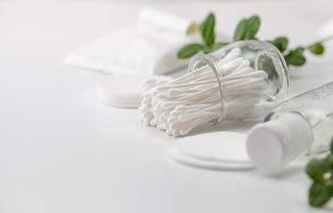 Fototapeta na wymiar Cotton buds in a jar, cotton pads and a sprig of green