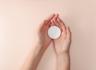 Cotton pad in the open palms of women's hands on a pink background © ekramar