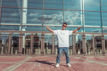 Man athlete, guy dancer in summer city. Glasses on background of glass windows. Fashionable modern...