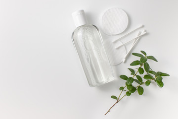 Micellar cleansing water in a bottle, cotton pads and a sprig of greenery