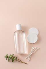 Micellar cleansing water in a bottle, cotton pads and a sprig of greenery