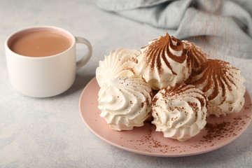 Airy vanilla zephyr on a pink plate, sprinkled with cocoa powder on top, a cup of fragrant cocoa and a gentle blue background.