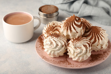 Delicious delicate zephyr sprinkled with cocoa powder, with a cup of hot cocoa, on alight blue   background.
