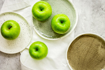 Healthy green food with apples on plates stone background top view