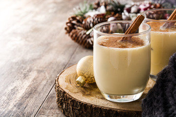 Homemade eggnog with cinnamon in glass on wooden table. Typical Christmas dessert. Copy space
