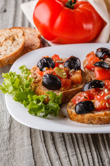 Italian bruschetta with tomato, black olives, lettuce and mustard