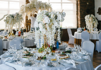 banquet round tables, decorated with a bouquet of white flowers in the center of the tables
