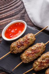 Shish kebab on the skewers with sauce on rustic table