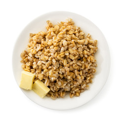Oatmeal with butter in a plate on a white. The view of the top.