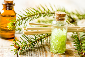 spa with organic spruce oil and sea salt in glass bottles on wooden table background