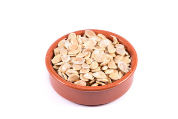 Pumpkin seeds in a ceramic bowl on isolated background