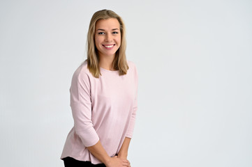 Fototapeta premium Close-up portrait of a cute caucasian blonde female student girl in pink blouse on a white background. Wide smile, happiness. It is in different poses.