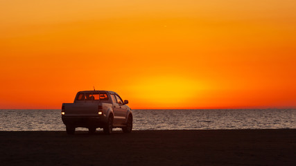 Pick-up truck parked in front of Black Sea at beautiful sunset.