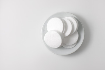 A pile of cotton pads in a plate on a gray background