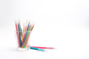 Group of color pencils in a white cup on an isolated background.