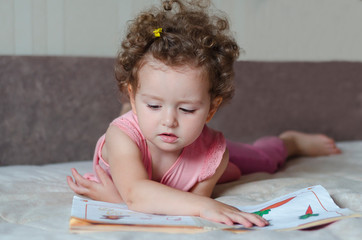 little cute girl with interest reads a children's book. child development.