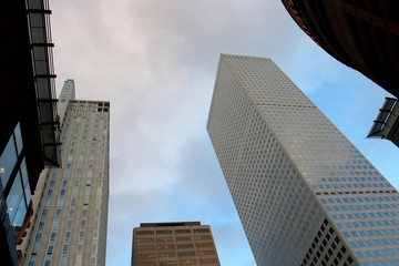 Urban cityscape and modern architecture background. Downtown upward street view with skyscrapers against morning cloudy blue sky in the central district of Denver, Colorado, USA.