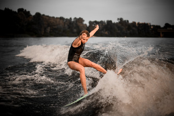 Active girl wakesurifing in the river near forest