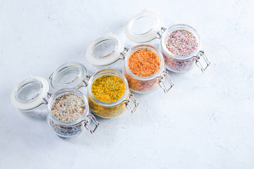 Obraz na płótnie Canvas Four jars with different flavoured mixes of salt and spices. Himalayan and sea salt mixed with various peppers and herbs.