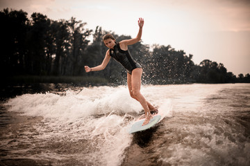 Young girl wakesurifing and gliding in the river near forest