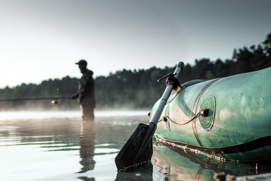 Inflatable boat on the lake at dawn, a fisherman at dawn fishing. Fishing hobby vacation concept. Copy space.