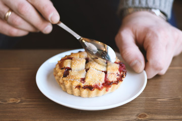 man in grey sweater drinks black lungo americano coffee in winter autumn in coffee shop eating classic american home-made cherry pie on white plate on wooden table. Fall mood instagram style