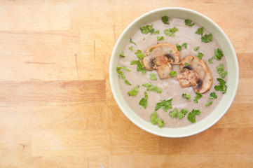 Mushroom cream soup with parsley, on wooden background, hot dish