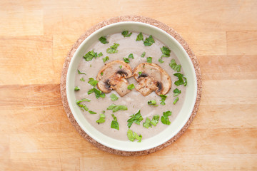 Mushroom cream soup with parsley, on wooden background. Hot dish. Top view, food.