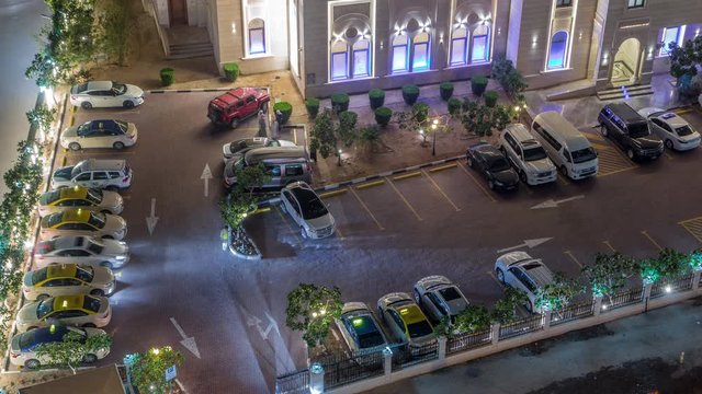 Cars moving on parking near Al Rahim Mosque in Dubai Marina aerial timelapse - illuminated religious building between skyscrapers from above