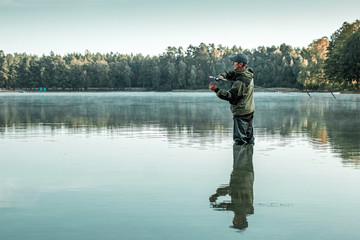 A male fisherman on the lake is standing in the water and fishing for a fishing rod. Fishing hobby...
