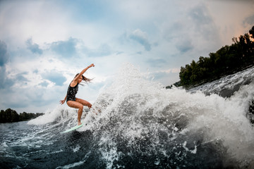 Female wakesurfer performing stunts on a board