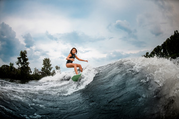Female wakesurfer making stunts on a board