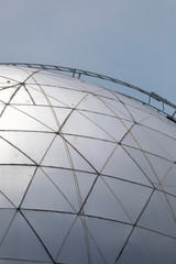 Space age modern silver dome structure with hexagonal and triangular patterns against a blue sky