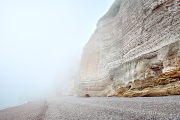 Misty morning fog at the rocky beach in Normandy with a lonely man at the background - 293417029