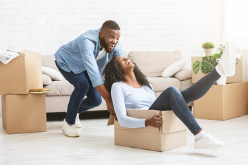 Playful man pushing box with his woman, moving in