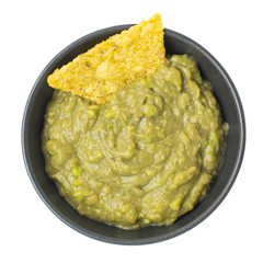 Green Guacamole with nachos in dark bowl isolated on white background. Top view