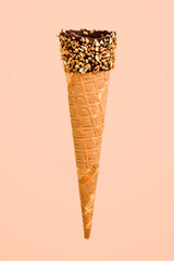 Empty cone with nuts and chocolate on a beige background with a copy space.