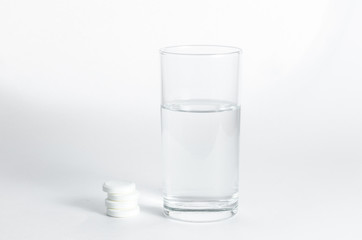 Transparent glass of water and soluble effervescent tablets isolated on white background. The concept of treatment and prevention of viral diseases. Help with depression and insomnia.Drinking medicine