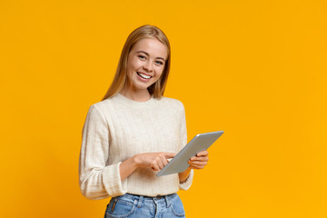 Smiling teenage girl holding digital tablet and looking to camera
