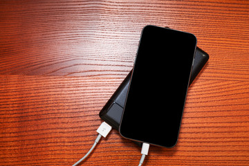 powerbank charges smartphone isolated on wood background