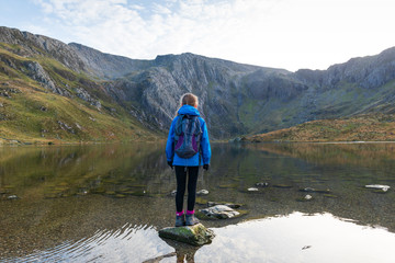 Tranquil scene of young girl looking away from camera out to mountain lake