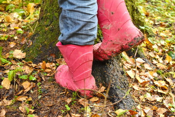 A child in red rubber boots in the fall.