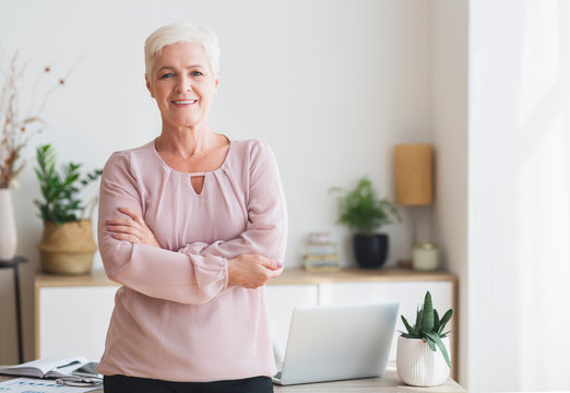 Successful senior woman posing over working place at home