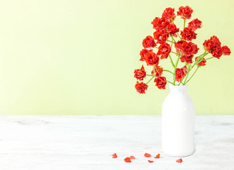 Roses in retro white vase on wood table on grunge blue wall with copy space.