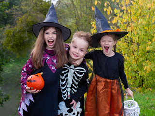 cute funny children in carnival costumes of witches and skeleton eat candy, have fun and celebrate the autumn traditional holiday Halloween, children's halloween party in the park concept