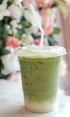 plastic cup of green tea with milk and flower decoration.