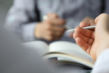 Hand of businessman in suit filling and signing with silver pen partnership agreement form clipped...